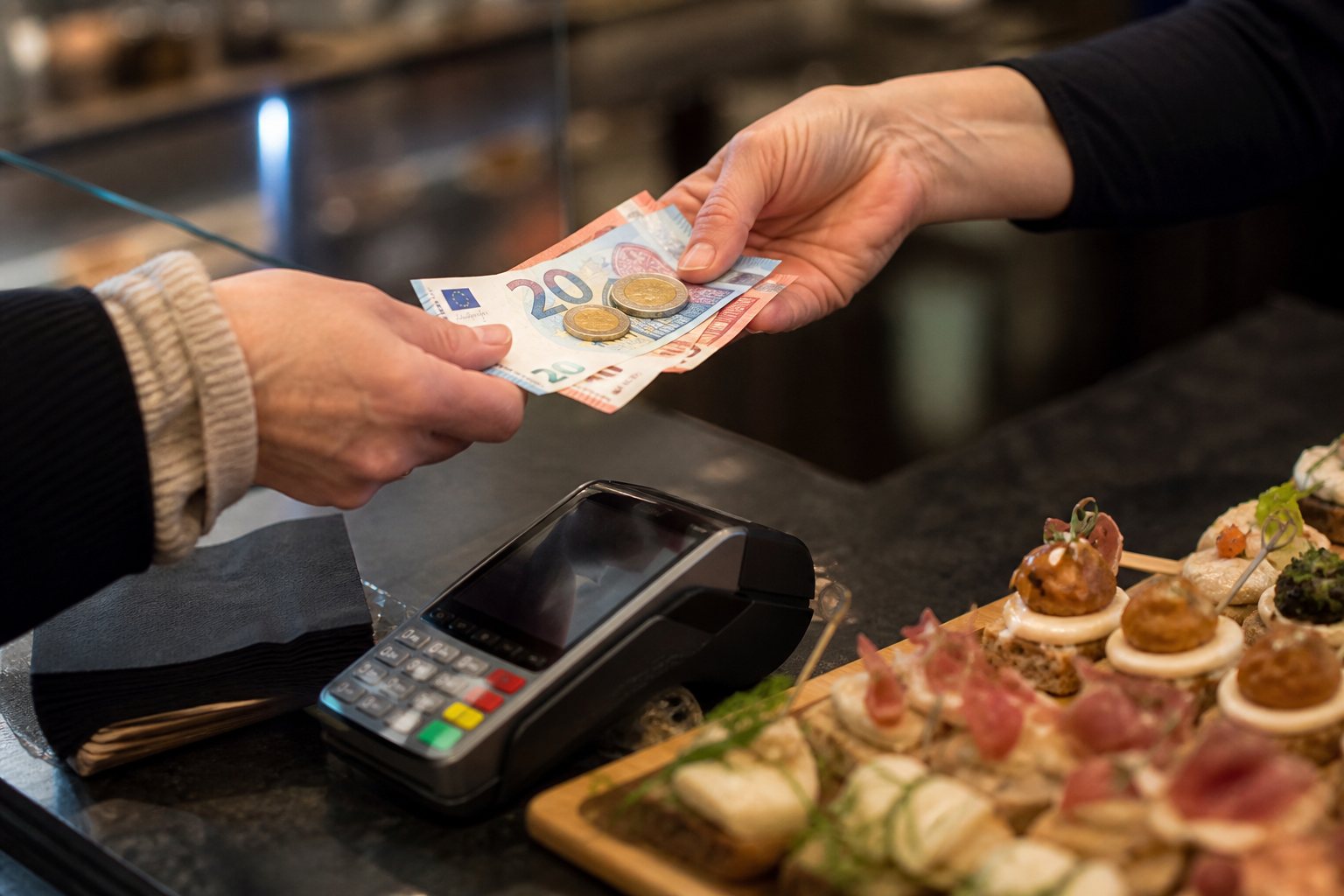 Gast betaalt met eurobiljetten en munten aan een buffet met een pinapparaat ernaast